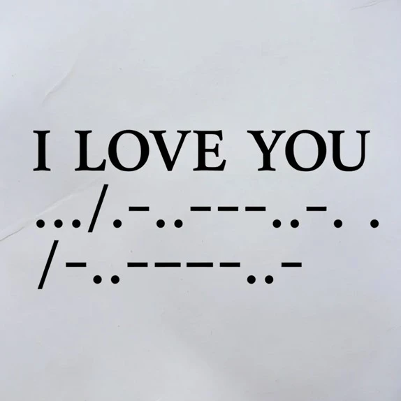 The phrase 'I LOVE YOU' printed in large bold text above its Morse code translation shown as dots and dashes across two lines on a white paper background.